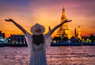 a woman in a white dress and hat with her arms up and hands up in