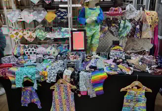 a table with a display of baby clothes and childrens clothing made by Distinctly individual