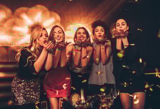 Group of stylish women blowing kisses surrounded by confetti during a glamorous night out on the Las Vegas Strip Crawl.