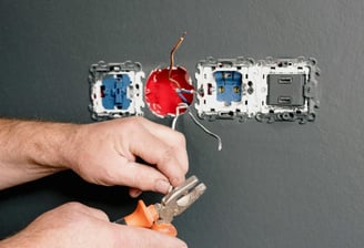 électricien installant une prise murale électrique