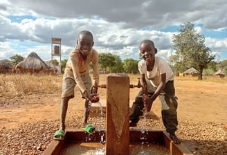 Children drinking clean water from a well in Africa