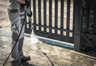 Homme utilisant un nettoyeur haute pression pour laver des pavés.