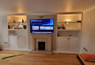 a large screen tv mounted on to a wall above a fireplace. Chelsea