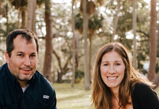 a man and woman sitting on a bench in a park