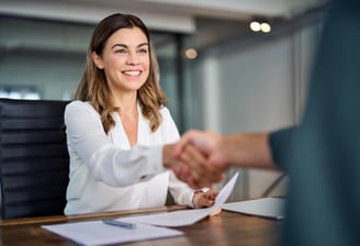 a woman in a white shirt and a man in a suit shaking hands