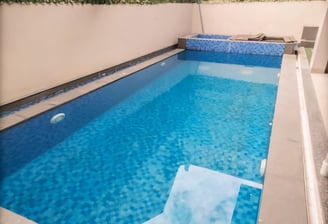 kolam renang minimalis di halaman belakang dengan finishing keramik roman berwarna biru