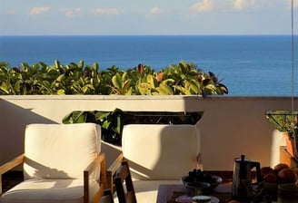 a balcony with a table and chairs and a view of the ocean