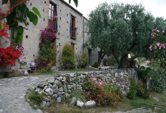 a stone wall with flowers and trees in front of a stone wall