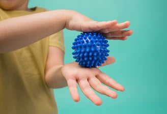 a child's hand holding a blue ball