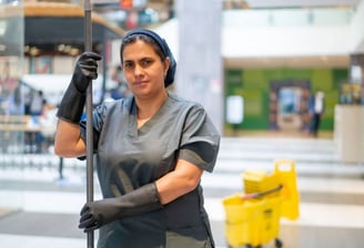 a woman in a black dress and gloves holding a mop