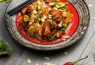 a plate of noodles with chopsticks and vegetables