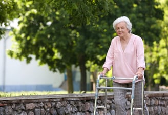 a woman with a walker frame walking outside - The London Physio