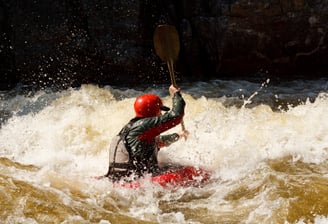 Man-in-red-helmet-paddling-on-water-in-a-boat