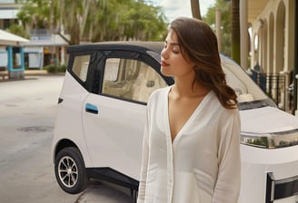 young woman stands in front of white Impulse Electromotive Nano-3 Micro EV car