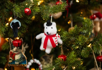 a teddy bear ornament hanging from a christmas tree