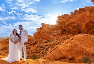 a bride and groom standing on a rocky mountain