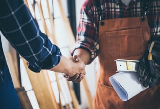 Männer in Arbeitskleidung, die sich freundlich die Hand reichen