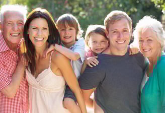 Multigenerational family smiling in front of their home – real estate and mortgage services for all