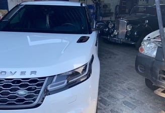 a white car parked in a garage with a man standing next to it