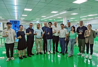 a group of people standing in a factory with thumbs up