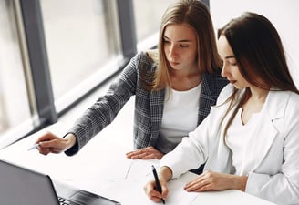 two women sitting at a desk discussing business