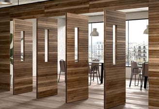 Puerta pivotante de gran formato en madera natural dentro de un espacio arquitectónico elegante
