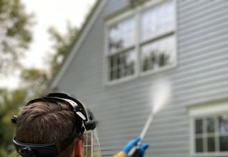 a man in a yellow jacket spraying a house
