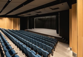 a theater stage with blue chairs and a stage