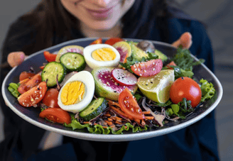 a woman holding a plate with a salad on it