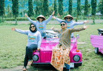 Wisatawan menikmati perjalanan VW Safari melewati pedesaan hijau dengan latar lapangan