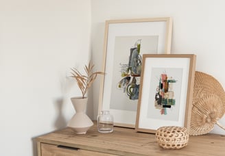 2 framed abstract mixed media art prints by Sweet Ruby Moon styled with neutral decor on a light wood dresser
