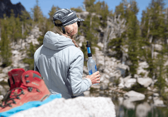 Hiker using Sawyer Mini Water Filter while hiking in the Rockies