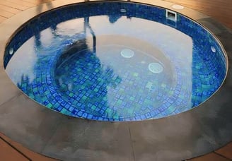 kolam jakuzzi dengan air panas berbentuk bulat dan mozaik kuda laut berwarna biru tua