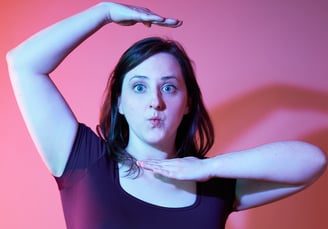 a woman with a fun expression and posture with pink background