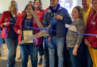 a group of people holding scissors and cutting a ribbon