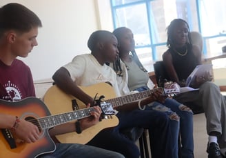 a group of people sitting around a guitar