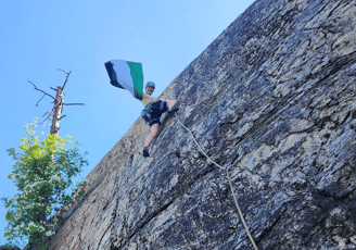 A climber halfway up the wall waving a Palestinian flag