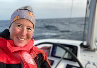 a woman smiling in a red jacket on a boat