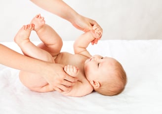 a baby is laying on a bed with a woman's hands