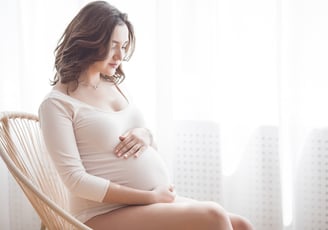 a pregnant woman sitting in a chair holding her belly
