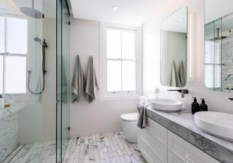 Modern en-suite bathroom featuring double vanity with two sinks, Calacatta marble tiles, glass panel