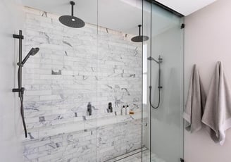 Modern en-suite bathroom featuring a glass-enclosed shower cubicle with dual rain shower
