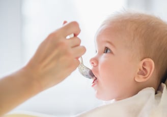 a baby is gets food with a spoon