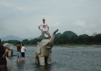 Nick Billington on an elephant  by the river in Guilin, China