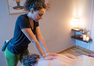 Masseuse bras tendus qui masse le dos d'un client avec bougies et décoration dans la pièce