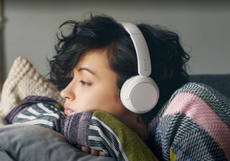 a woman laying on a couch with headphones on