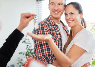 un homme et une femme tenant les clés d'une maison