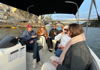 Guests chatting with Captain Francisco on Endure, with Porto’s Dom Luís I Bridge in the background