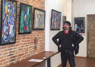 Julien Berger BERG debout devant ses tableaux dans la galerie le Bocal Toulouse