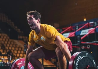 a man in a yellow shirt is holding a barbell